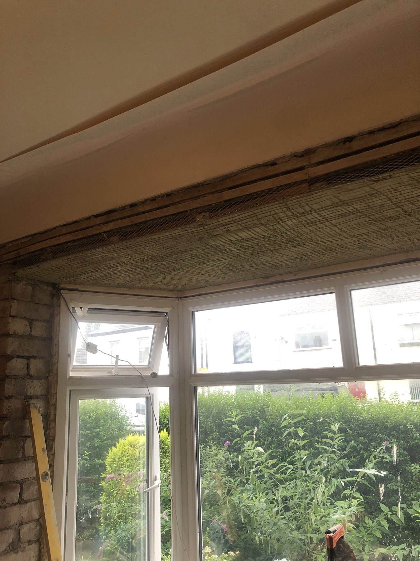 A bay window with the ceiling taken down to the laths and the brick showing