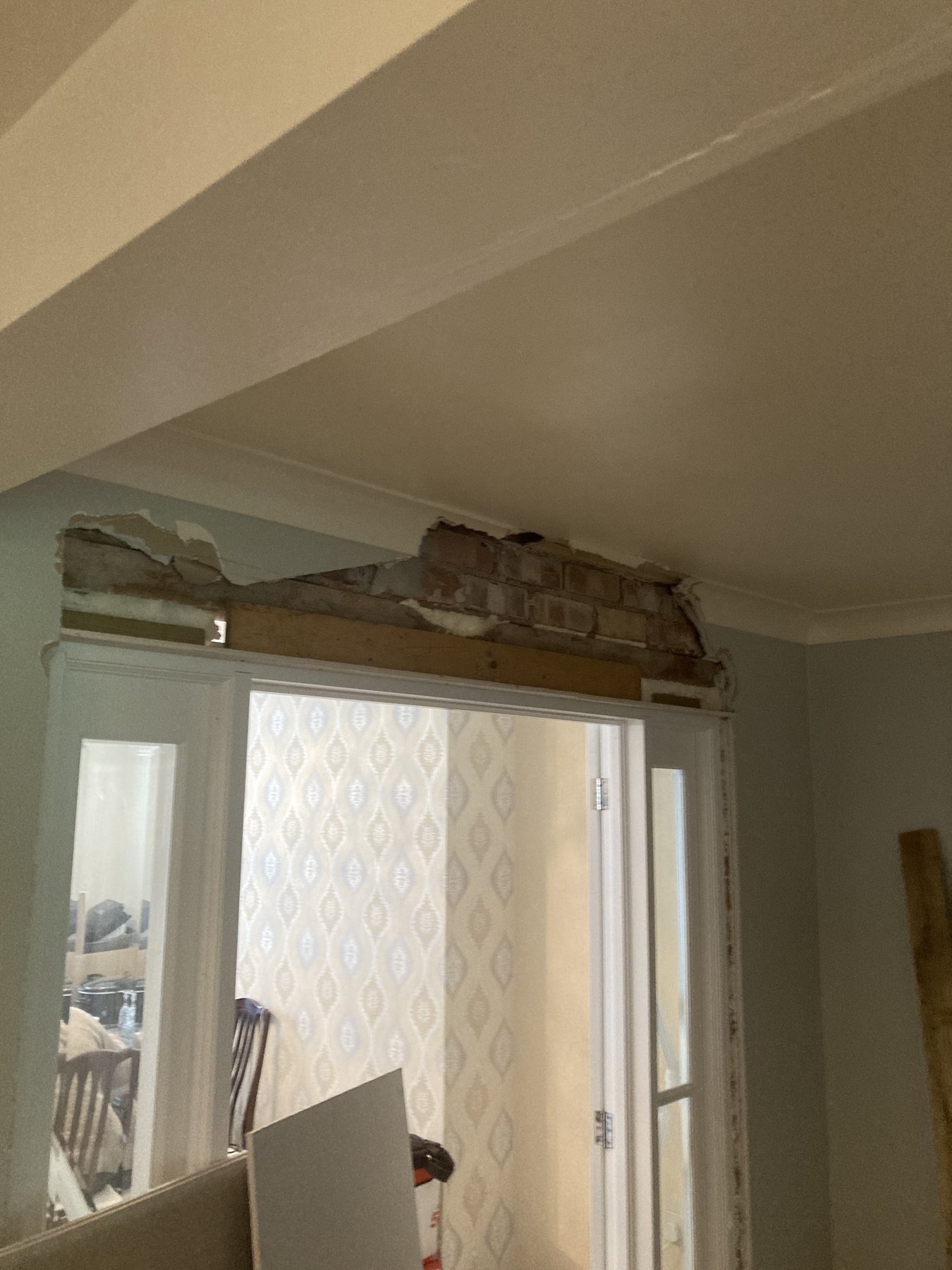 The wall above a pair of glazed doors with the plaster off, brick and timber showing