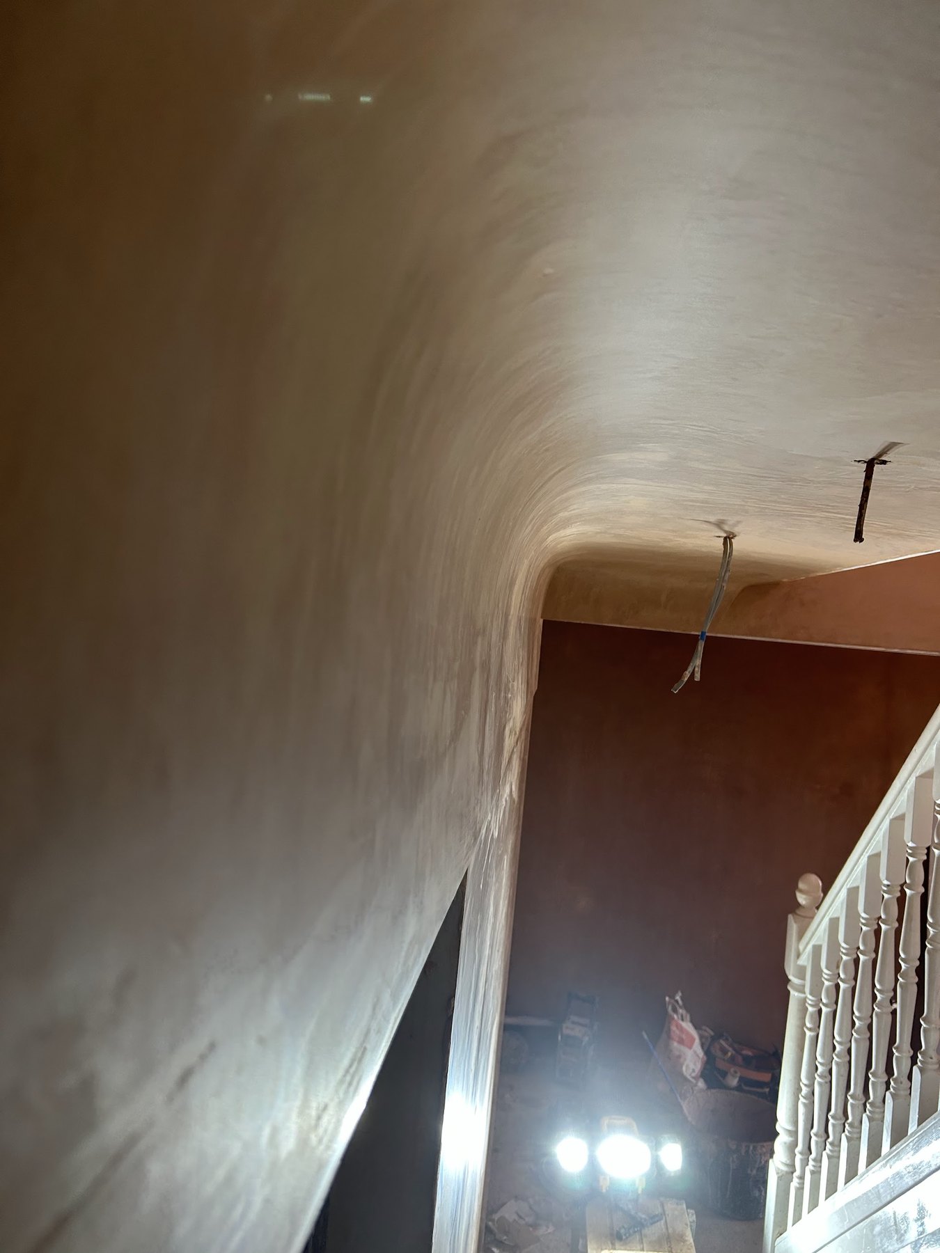 A stairwell wall and ceiling skimmed smooth, looking down the stairs